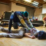 A person lying on the ground being held down by someone else
